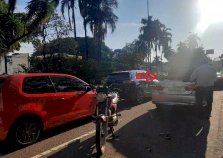 Motociclista bate em traseira de carro e vai parar sobre porta-malas