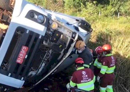 Carreta tomba e motorista fica com as pernas presas às ferragens