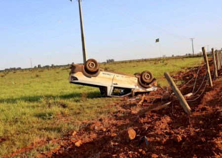 Picape com dois ocupantes capota, arrebenta cerca, e sai de estrada